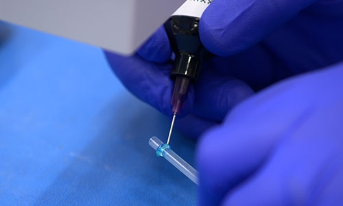 Dymax adhesive formulated with See-Cure technology being dispensed onto substrate.